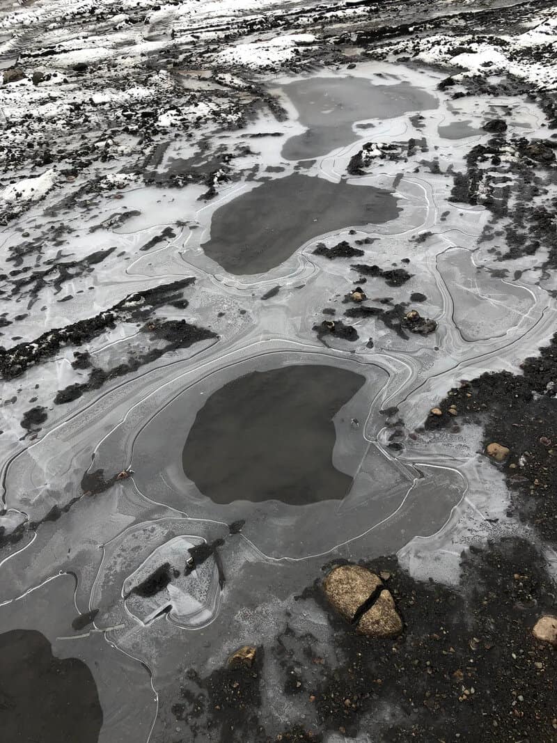Frozen puddles on the ground resembling abstract shapes and faces.