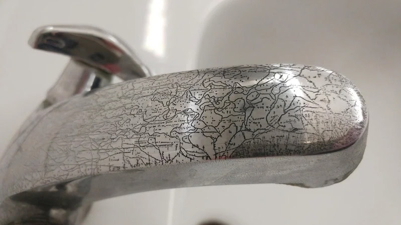 Close-up of a silver faucet with cracked and peeling surface.