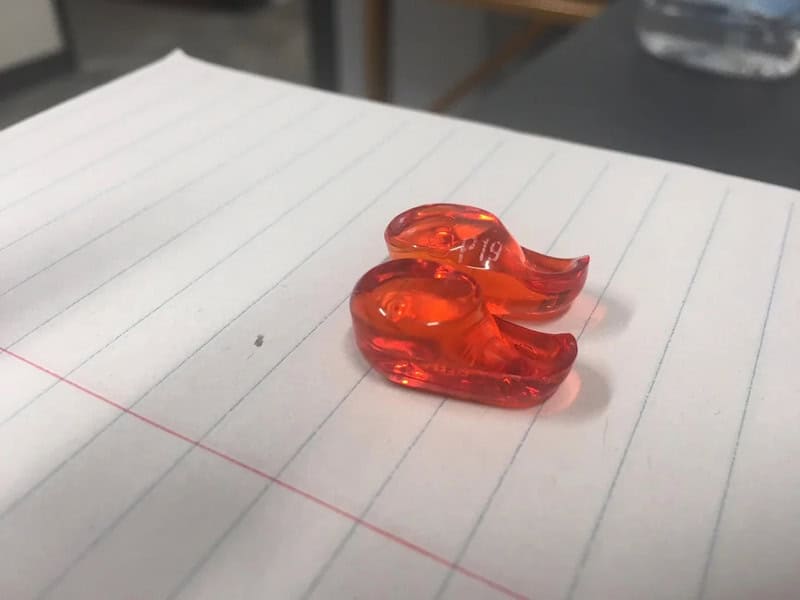 Red glass objects resembling a pair of eyes on lined paper.