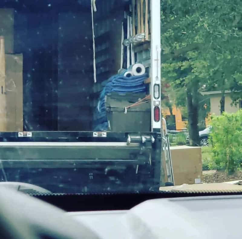 A moving truck with a blue mop and two googly eyes on top, resembling a face.