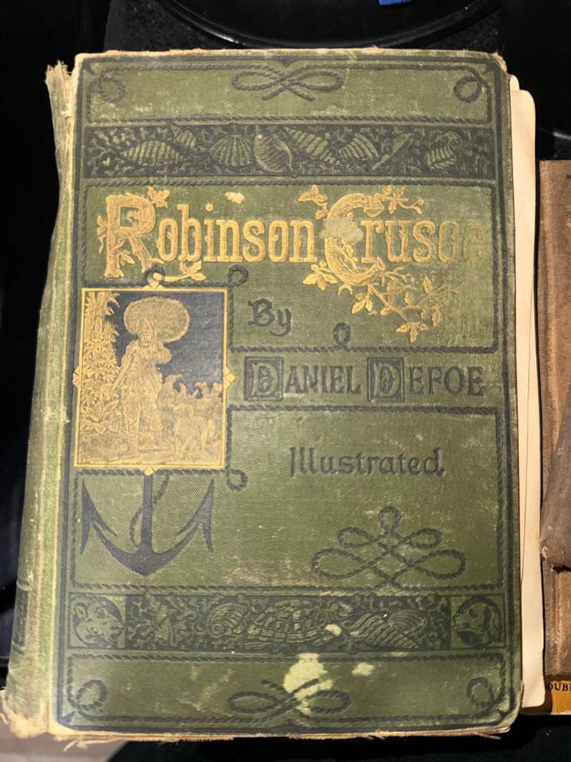 Old green book titled 'Robinson Crusoe' by Daniel Defoe with worn cover.
