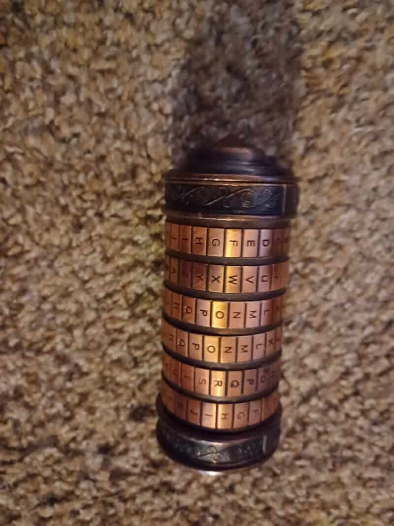 Vintage cipher wheel with rotating disks on a beige carpet.