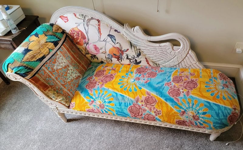 Ornate white vintage chaise lounge with colorful floral and patterned upholstery.