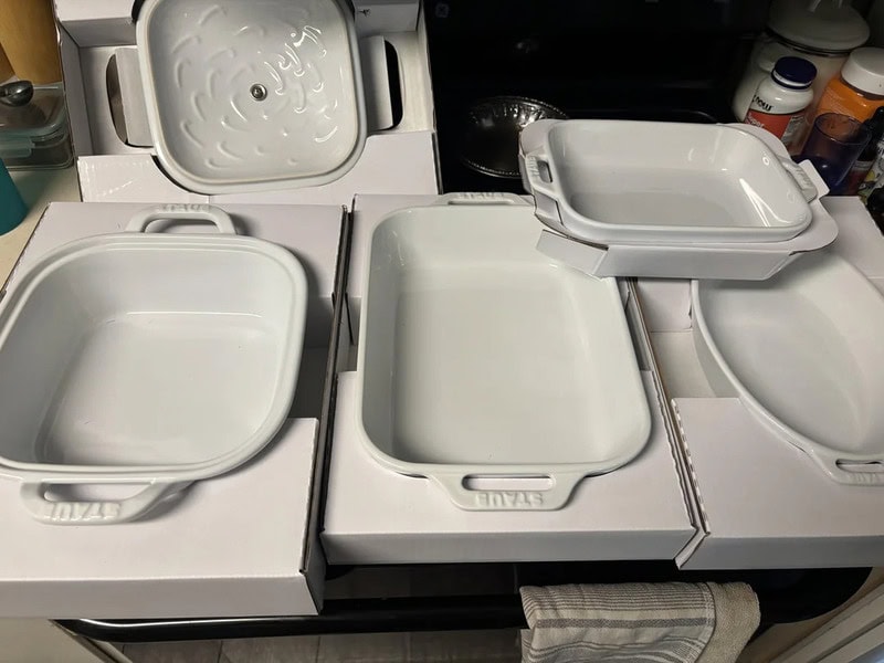White ceramic baking dishes on a kitchen counter, some in boxes.