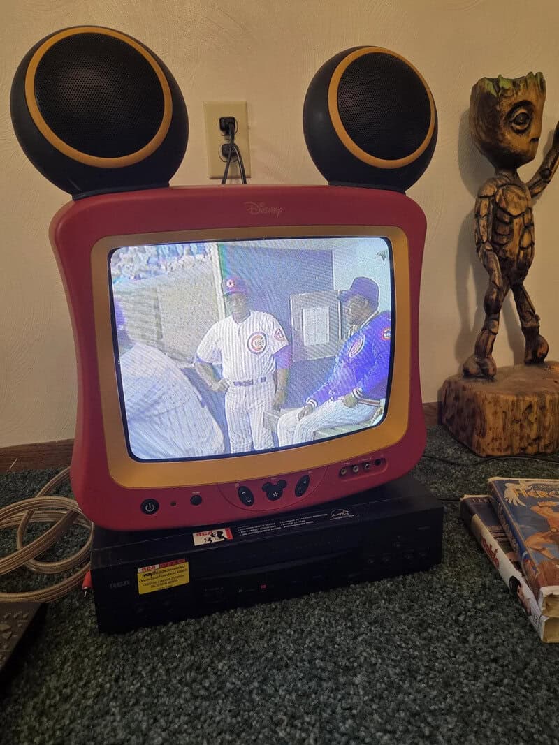 Pink Disney TV with two large black speakers on top, playing a baseball game.