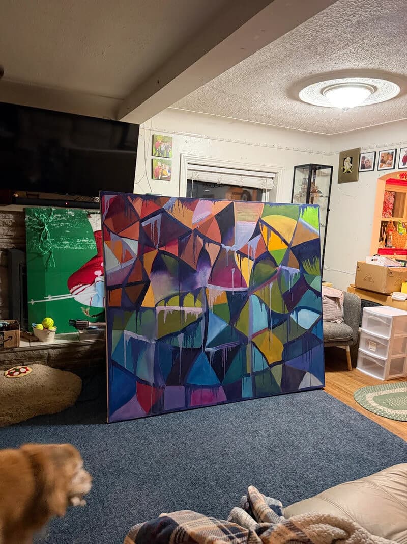 Colorful abstract painting leaning against a wall in a living room.