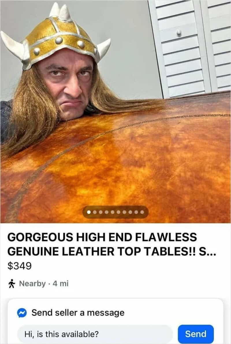 Man with long hair wearing a Viking helmet, peeking over a leather top table.