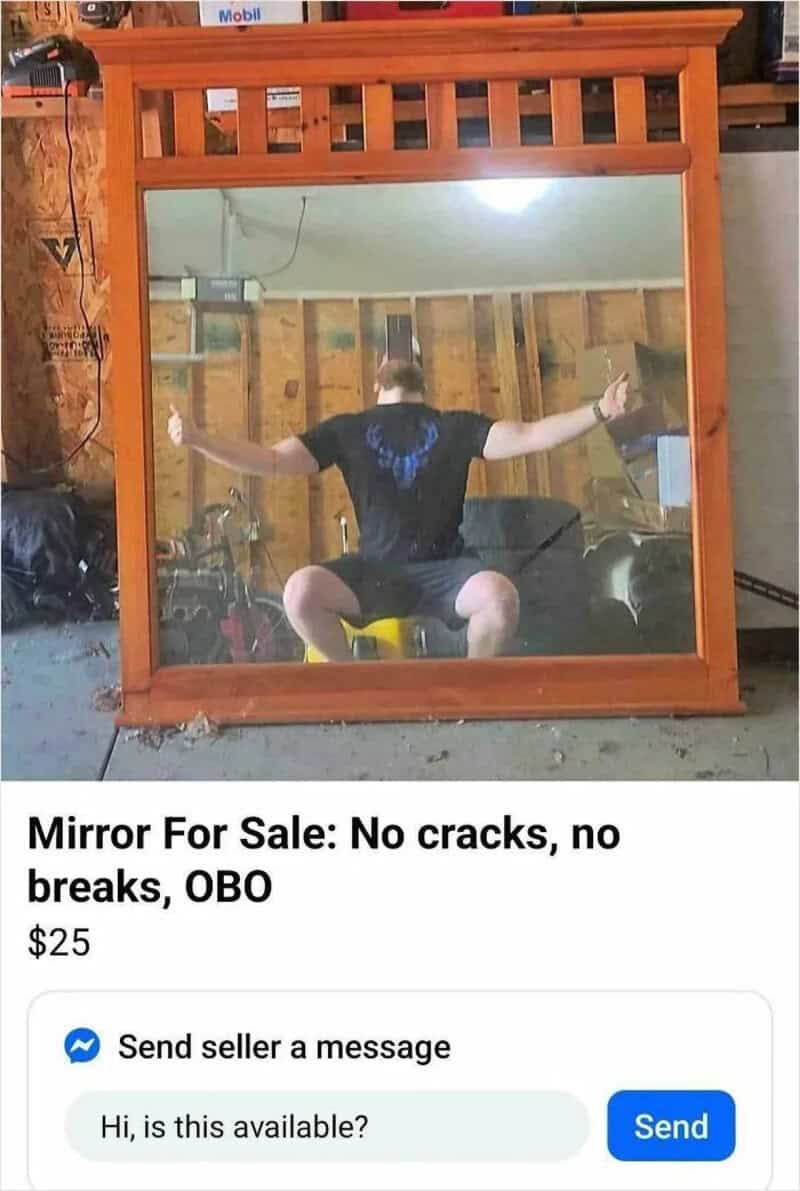 Large wooden mirror with a person reflected in it, no cracks or breaks.