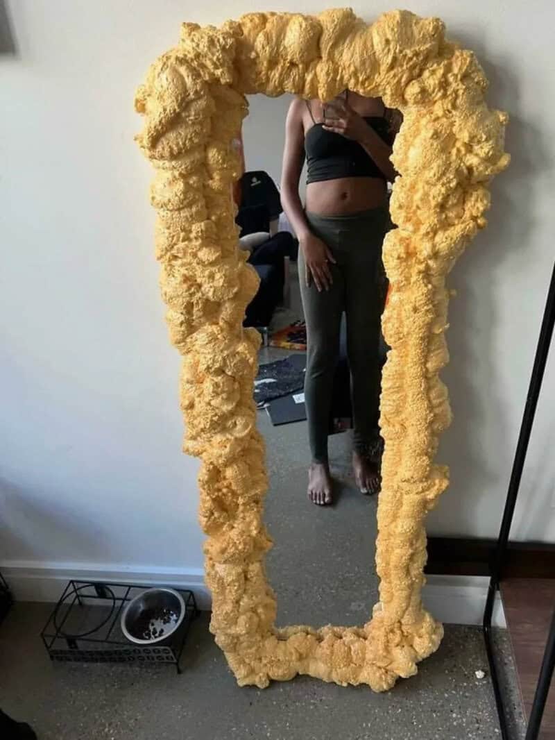 Person taking a mirror selfie with a fluffy yellow frame mirror.