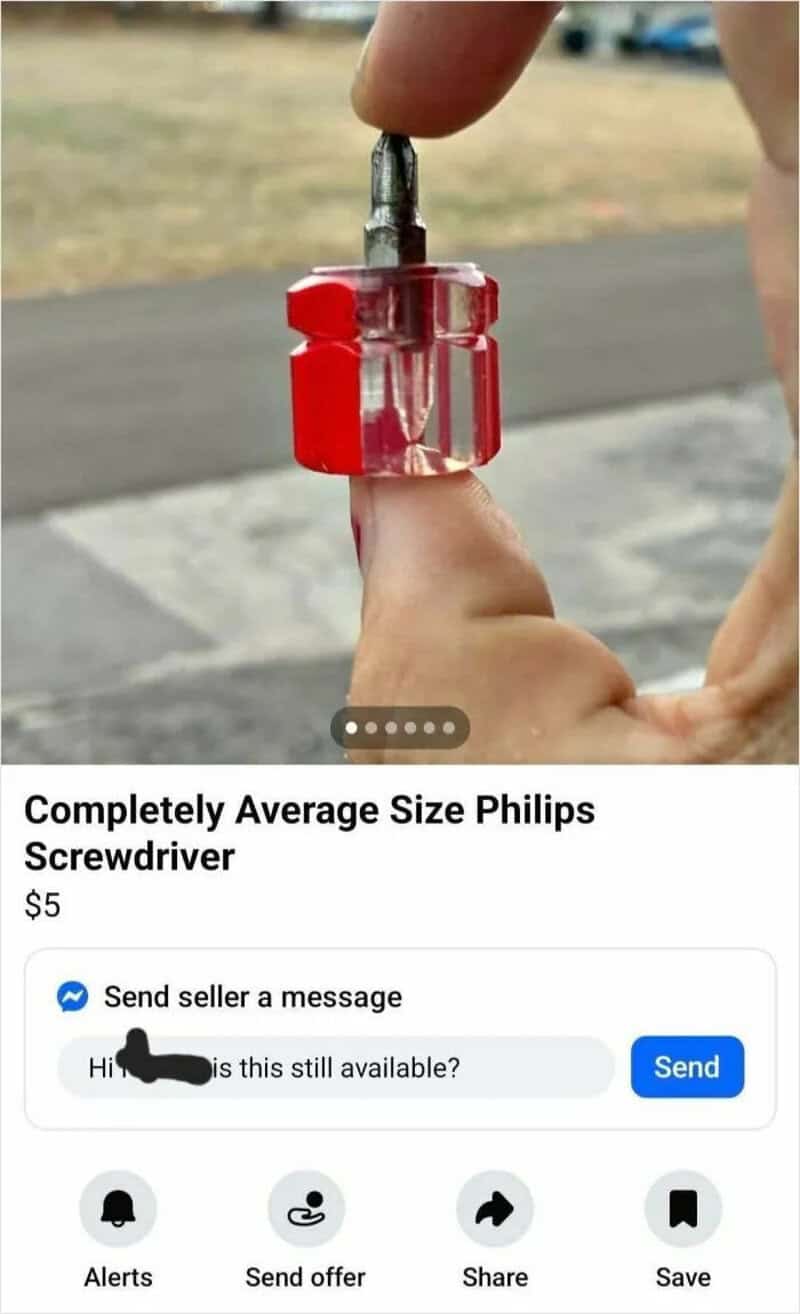 Close-up of a small Phillips screwdriver with a red handle, held by a person's hand.