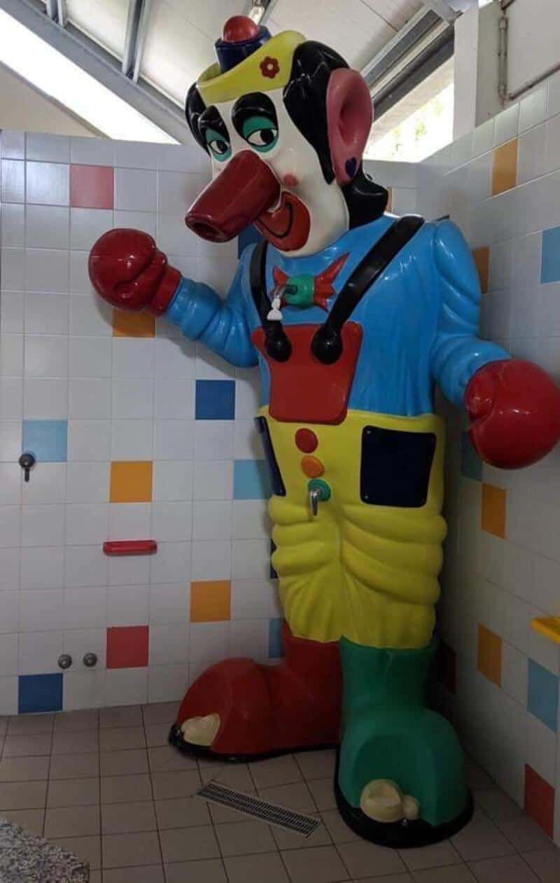 Colorful clown statue with exaggerated features in a tiled room.