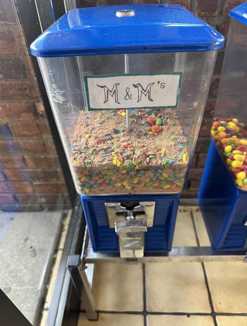 Gumball machine with colorful candies and a sign that says 'M & M's'.