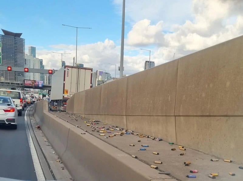 Litter and cigarette butts scattered on highway barrier in city traffic.