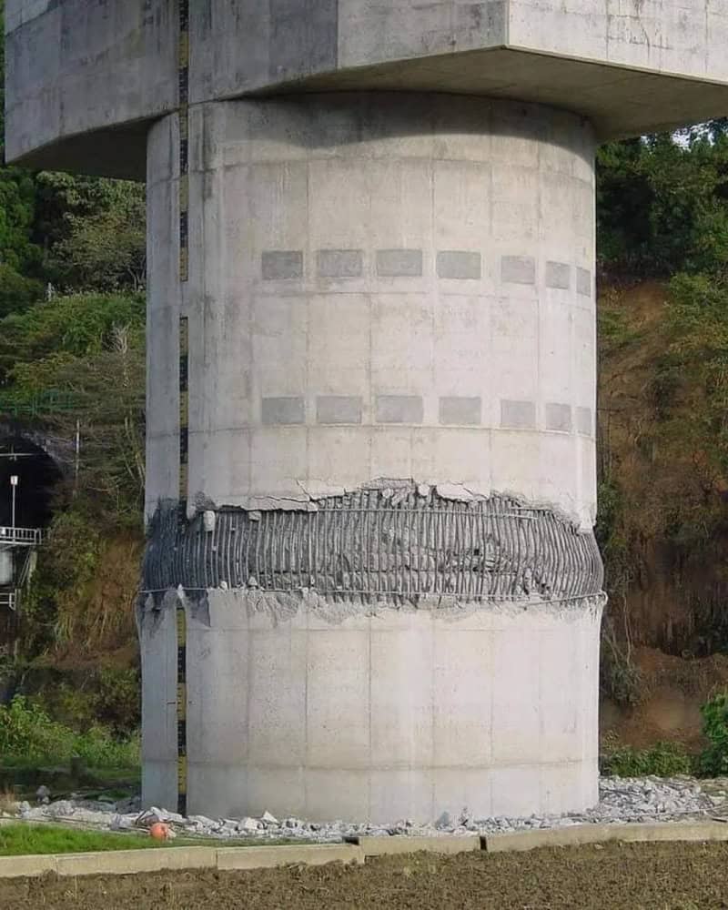 Concrete pillar with a damaged horizontal section and a measuring scale on the side.