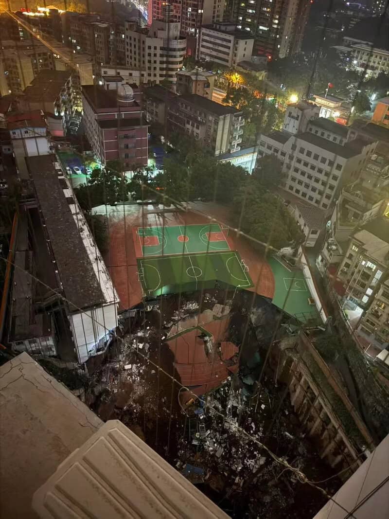 Night view of a city with a damaged basketball court and surrounding buildings.