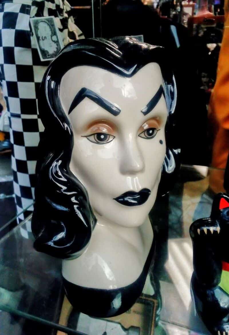 Portrait of a vintage black-haired woman mannequin head with bold makeup and a small black dot on a.