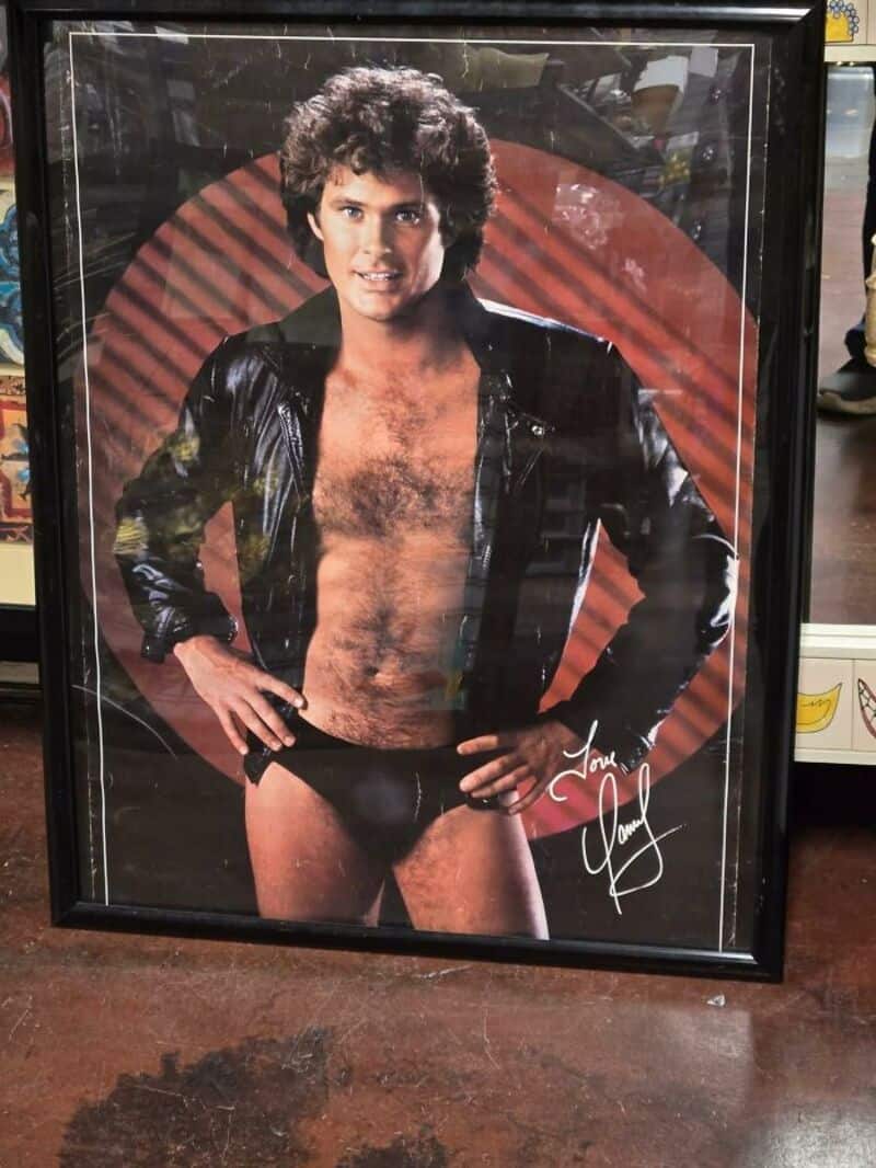 Male model with open black leather jacket and underwear, hands on hips, signature on bottom right.