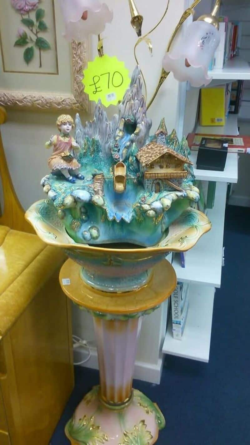 Decorative ceramic centerpiece featuring a blue waterfall with a small house and figurines, atop a 2.