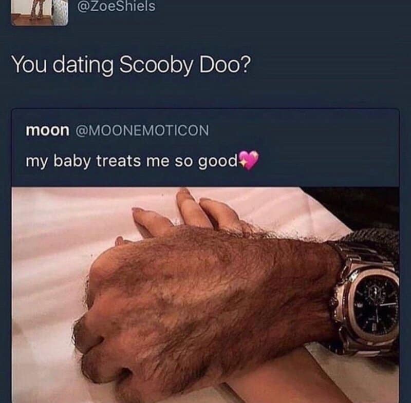 A hand with a watch holding a dog's paw, with a tweet about Scooby Doo and a pink heart.