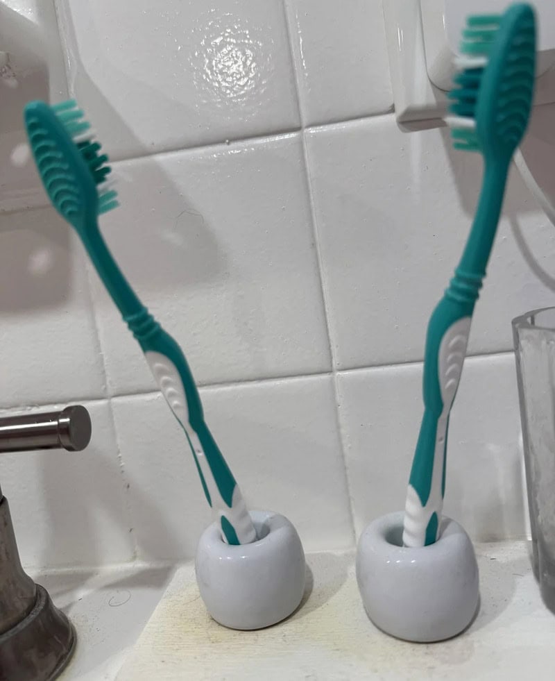 Two toothbrushes in small white holders on a bathroom counter.