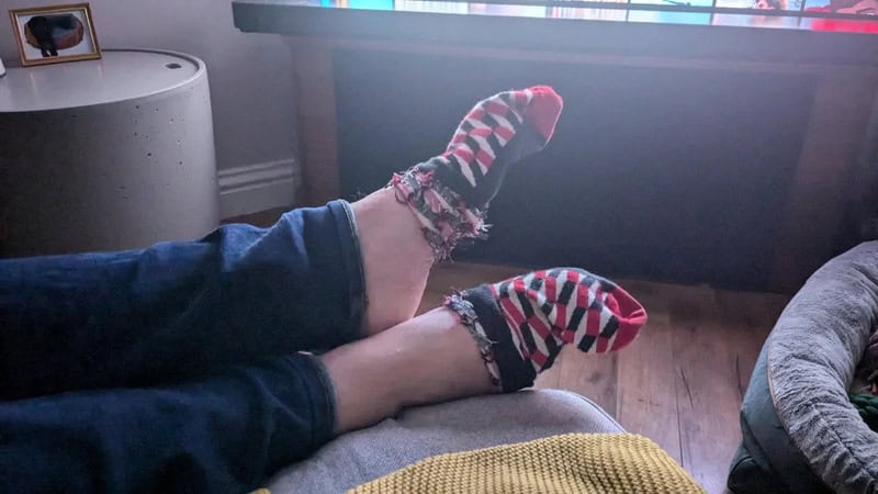 Person with legs up on the couch wearing colorful striped socks.