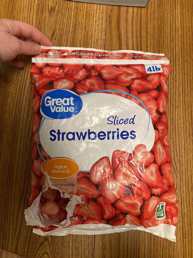 Bag of sliced strawberries on a wooden table, 4lb size, Great Value brand.