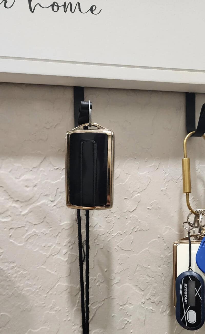 Black and gold portable charger hanging on a wall hook.