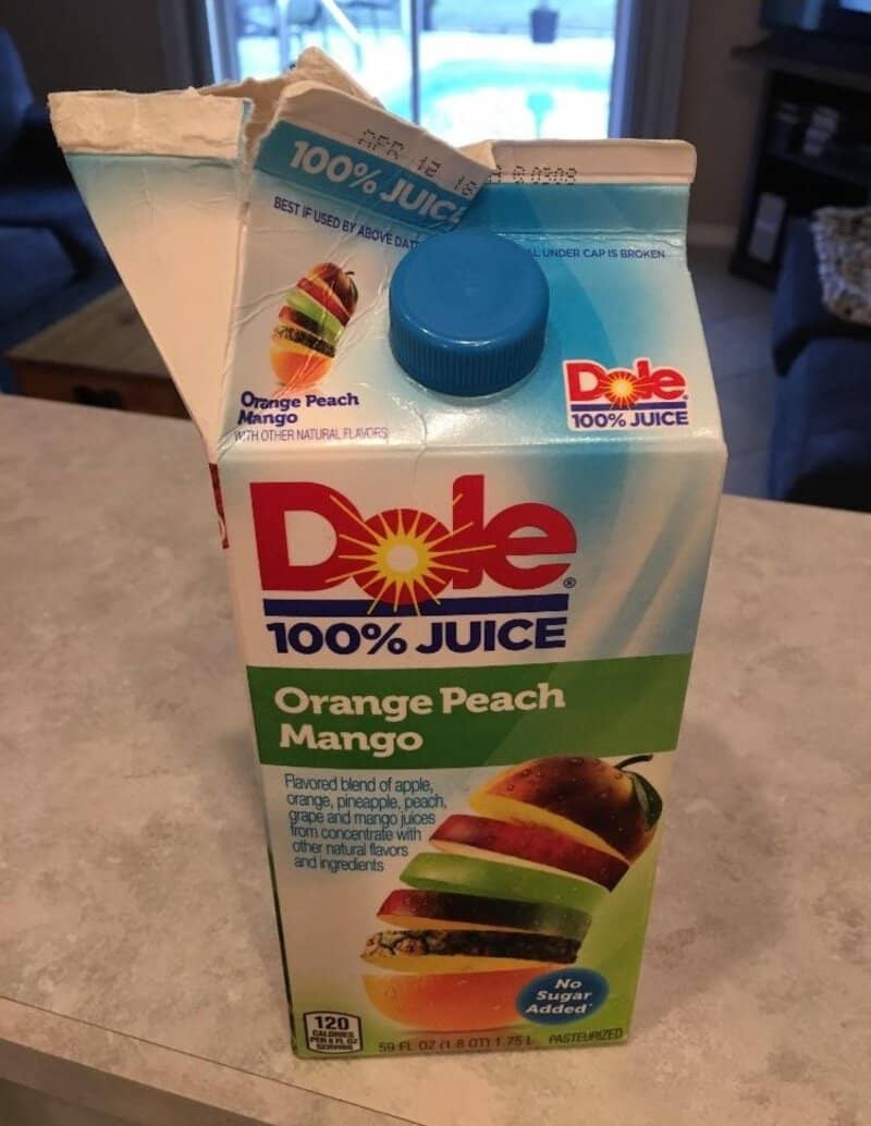 Open carton of Dole 100% Juice Orange Peach Mango with a straw inserted.